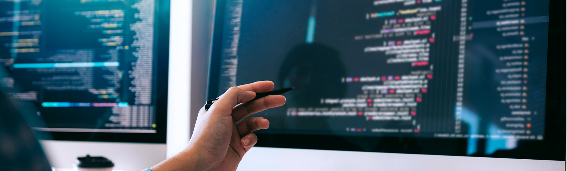 Imatge d'una persona treballant amb diversos monitors que mostren codi i elements de desenvolupament web